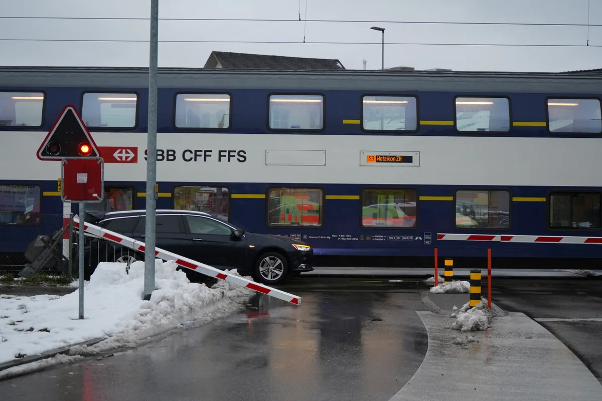 Ein Auto, das von einem Zug bei einer Barriere eingeklemmt wurde.